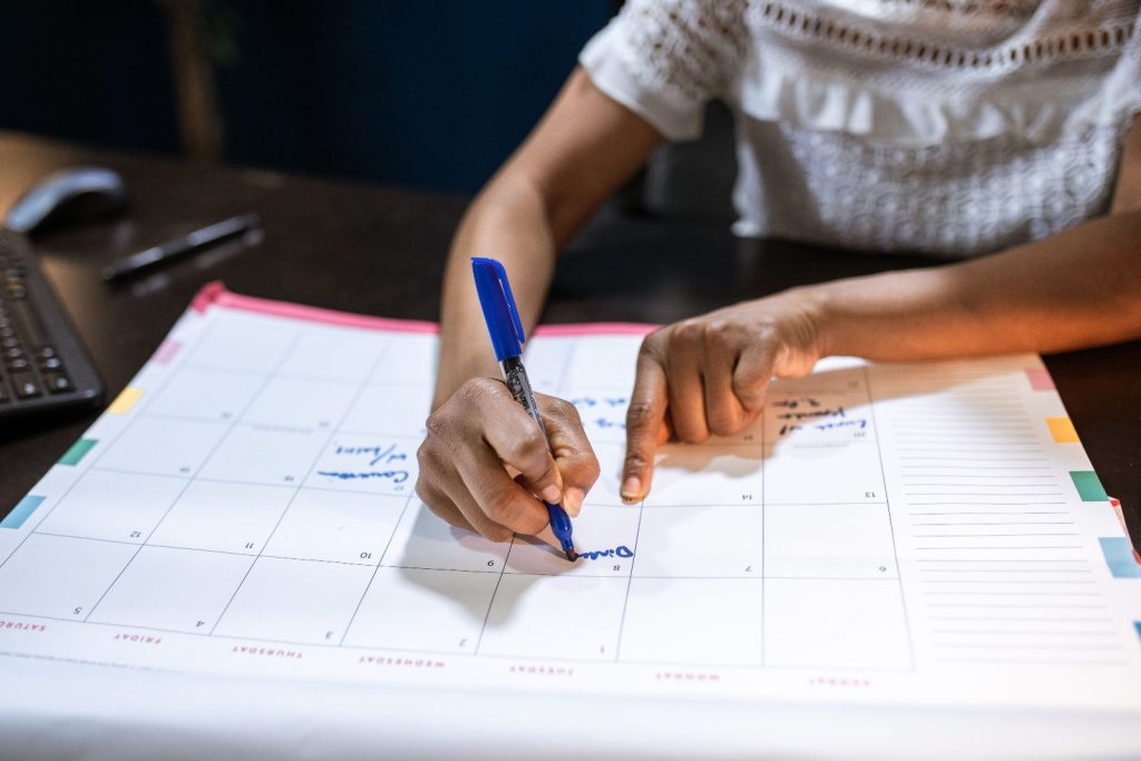 Woman marking important dates on a desk calendar while planning a university application timeline