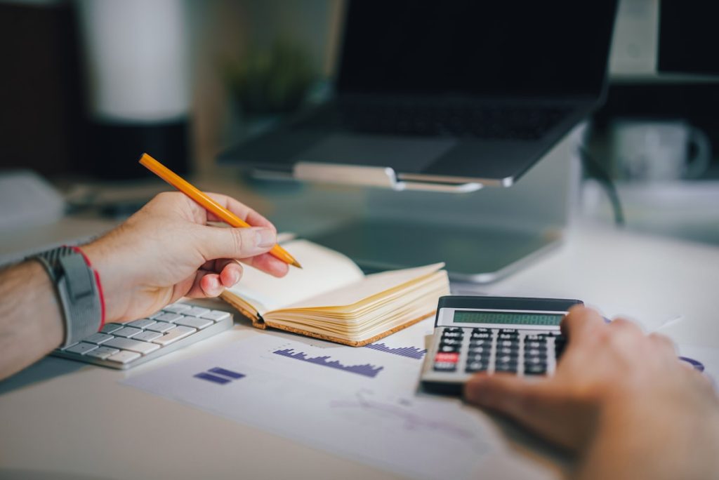 Student calculating a study abroad budget using a notebook and calculator